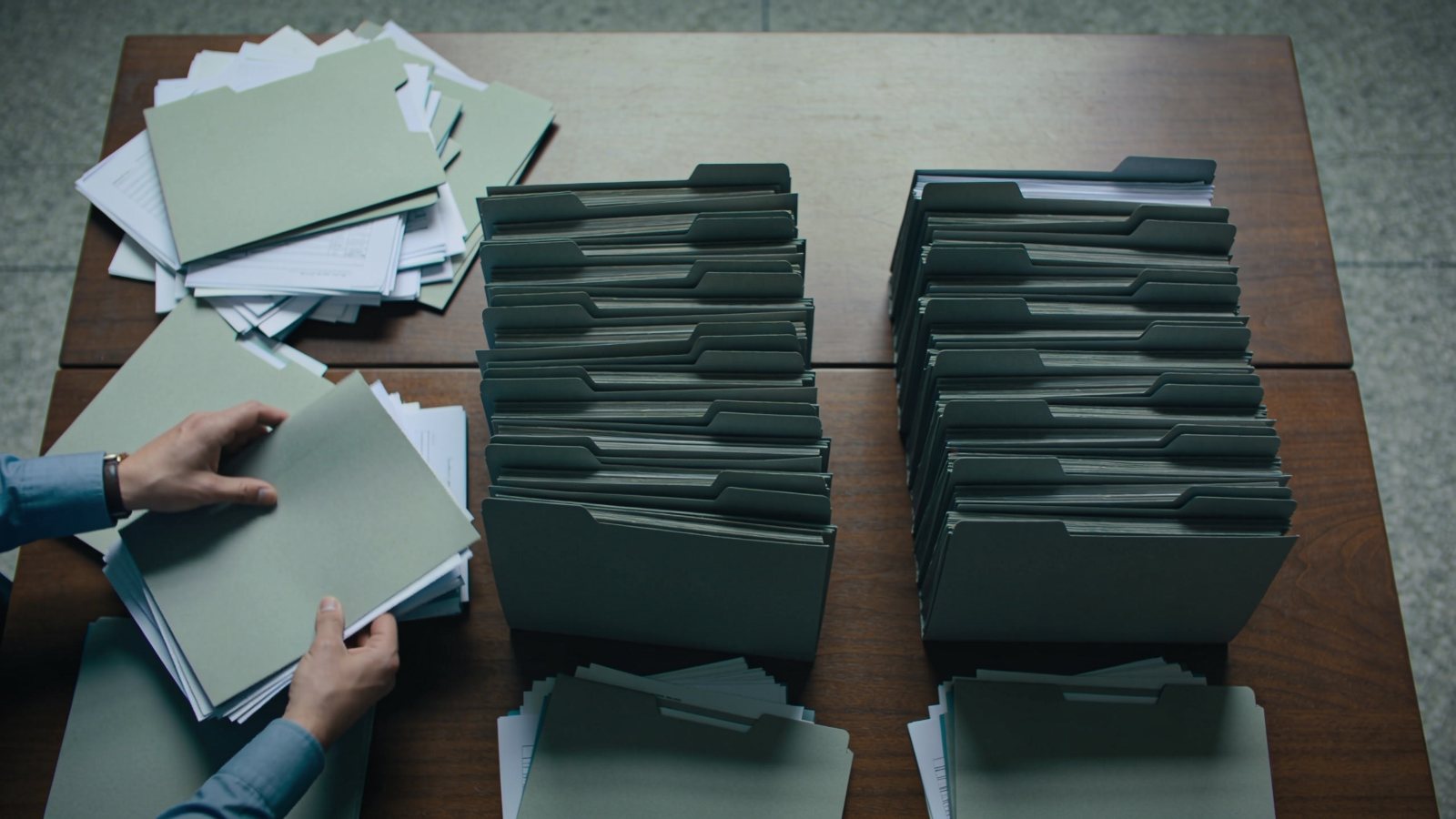 Hands sorting scattered document folders into ordered stacks